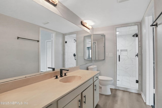 bathroom featuring wood finished floors, a marble finish shower, vanity, baseboards, and toilet