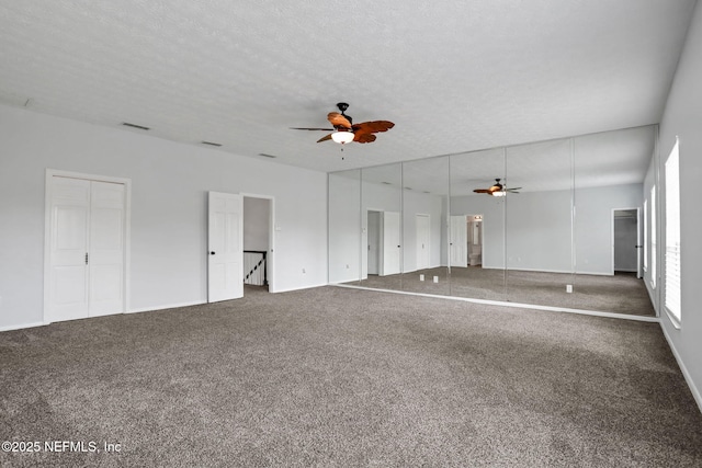 unfurnished living room with carpet flooring, visible vents, a textured ceiling, and ceiling fan