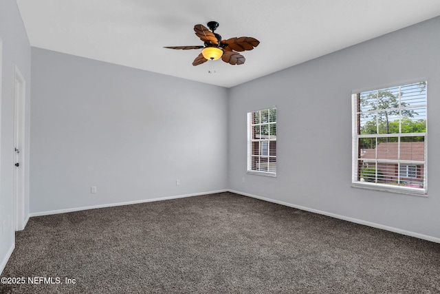 carpeted empty room with ceiling fan, a wealth of natural light, and baseboards