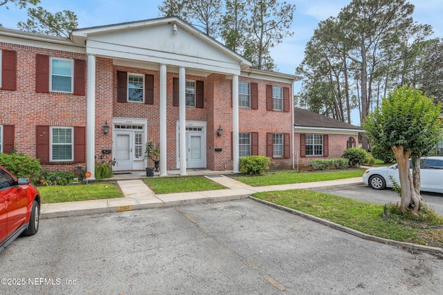 neoclassical / greek revival house featuring brick siding and uncovered parking