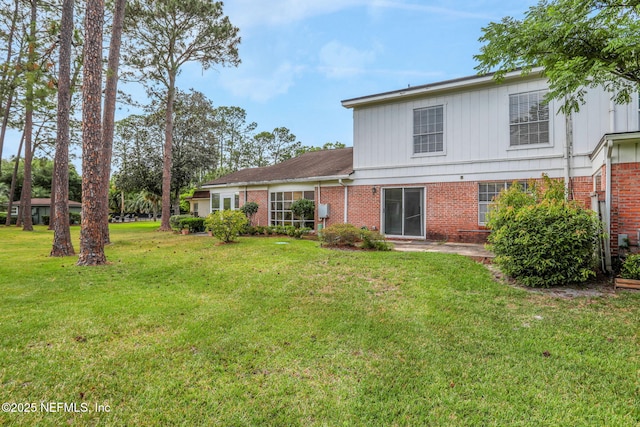 back of house with a lawn and brick siding