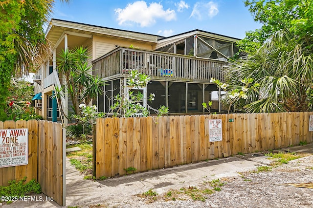exterior space featuring a balcony, a fenced front yard, and a sunroom