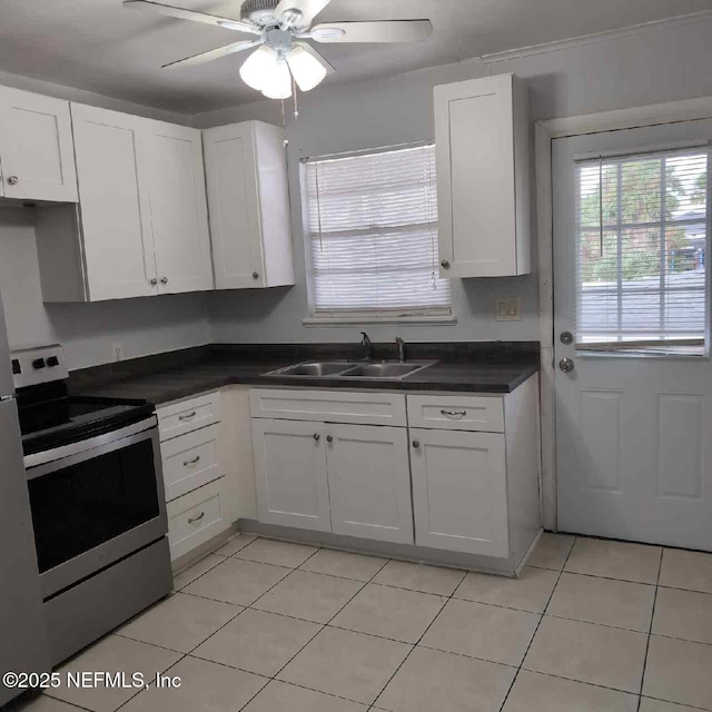 kitchen featuring light tile patterned floors, a sink, stainless steel electric stove, and white cabinetry