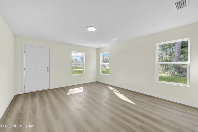 unfurnished room featuring baseboards, light wood-style floors, and visible vents
