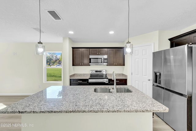 kitchen featuring dark brown cabinets, stainless steel appliances, visible vents, and light wood-style floors