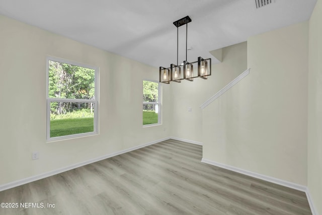 unfurnished dining area featuring visible vents, baseboards, wood finished floors, and an inviting chandelier