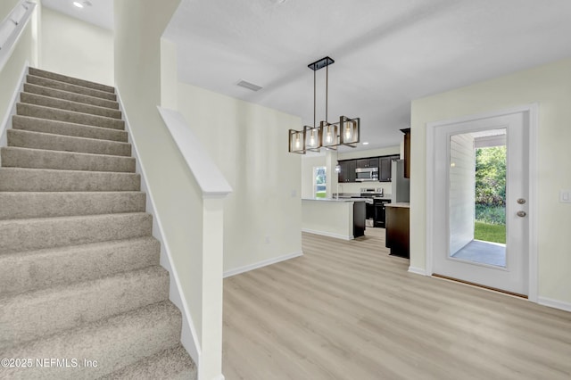 staircase featuring a wealth of natural light, wood finished floors, visible vents, and baseboards