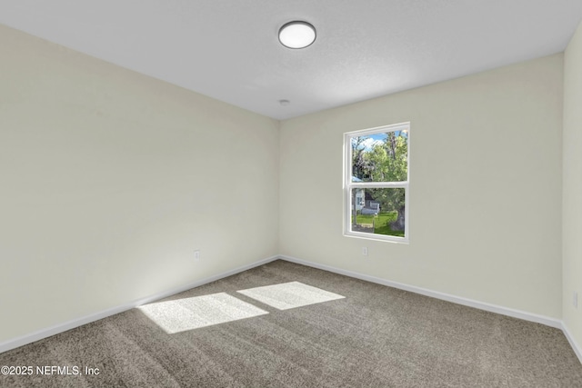 spare room featuring carpet and baseboards