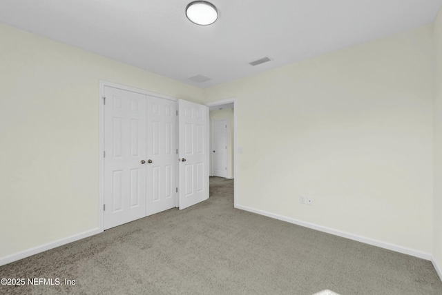 unfurnished bedroom with a closet, carpet floors, visible vents, and baseboards