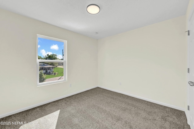 carpeted empty room featuring baseboards