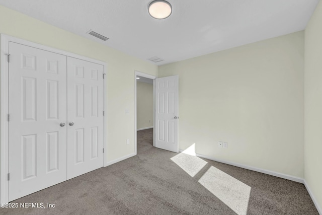 unfurnished bedroom with baseboards, visible vents, carpet floors, and a closet