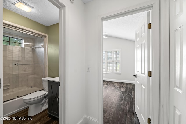 full bath featuring wood finished floors, a textured ceiling, toilet, and a healthy amount of sunlight