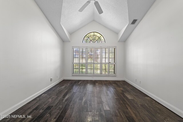 spare room with vaulted ceiling, visible vents, dark wood-type flooring, a textured ceiling, and ceiling fan