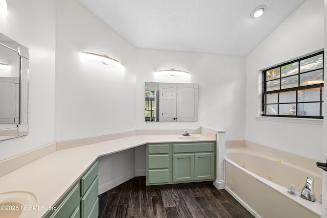 bathroom featuring wood finished floors, a textured ceiling, vanity, and a tub with jets