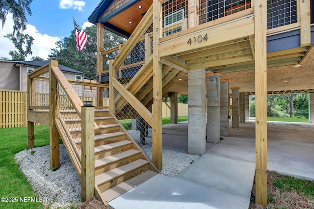 exterior space featuring a wooden deck, a carport, stairs, and fence