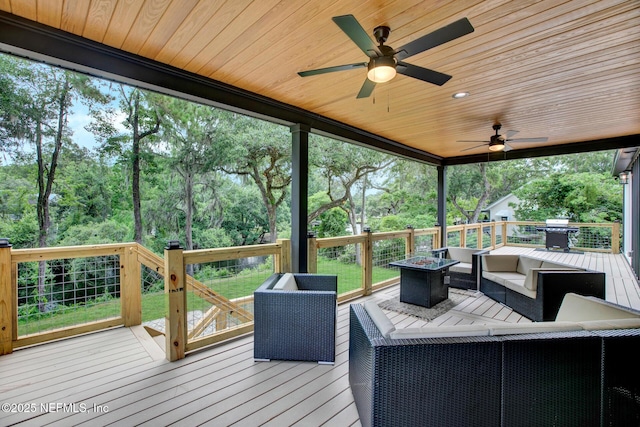wooden terrace with a ceiling fan, an outdoor living space with a fire pit, and area for grilling