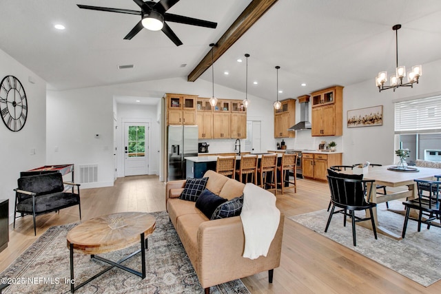 living area featuring light wood finished floors, vaulted ceiling with beams, visible vents, and ceiling fan with notable chandelier