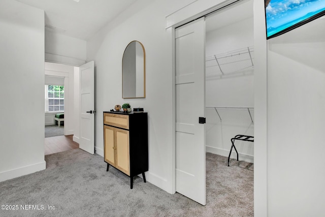 hall featuring light colored carpet and baseboards