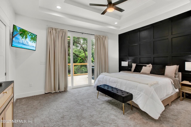 bedroom with a decorative wall, a raised ceiling, light colored carpet, access to exterior, and recessed lighting