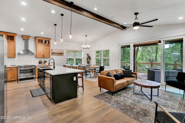 kitchen with light countertops, wall chimney range hood, vaulted ceiling with beams, light wood-style floors, and appliances with stainless steel finishes