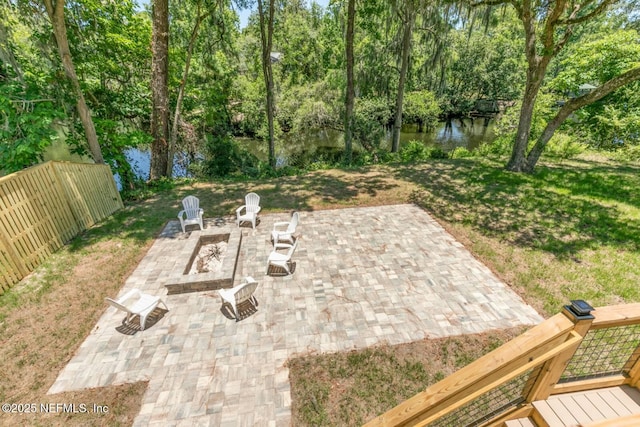 view of patio / terrace featuring fence, a fire pit, and a water view
