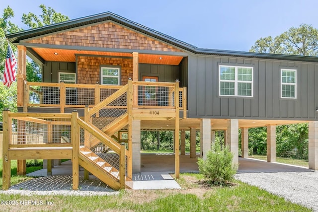 rear view of house featuring board and batten siding, driveway, a carport, and stairway