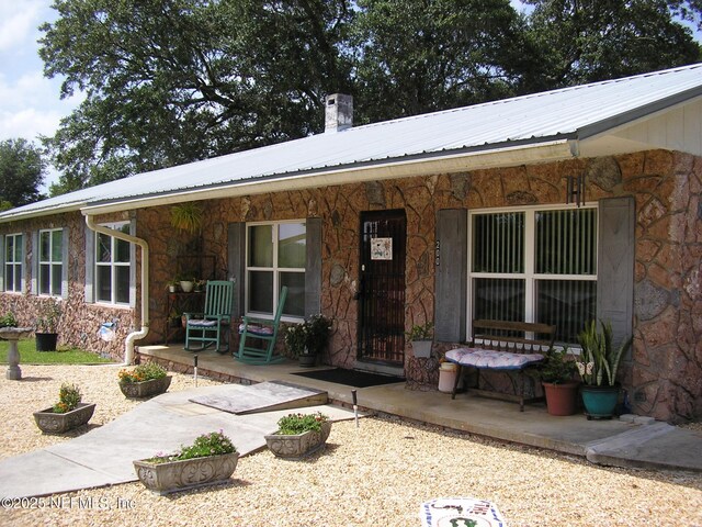 view of front of home with a porch, stone siding, and metal roof