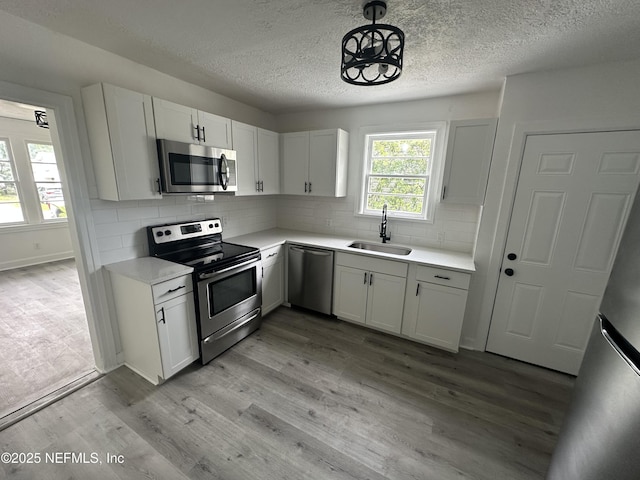 4848 Sappho Ave, Jacksonville, FL 32205 - kitchen with stainless steel appliances, a sink, a textured ceiling, light wood-type flooring, and light countertops