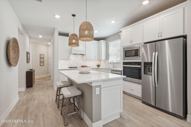 kitchen with backsplash, appliances with stainless steel finishes, a center island, and white cabinetry