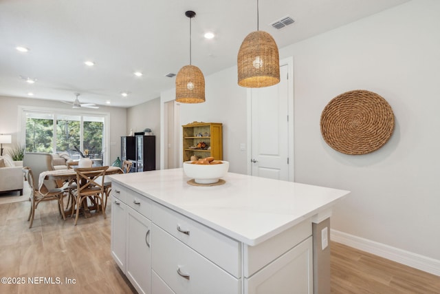 kitchen with a center island, open floor plan, light wood-type flooring, white cabinetry, and visible vents