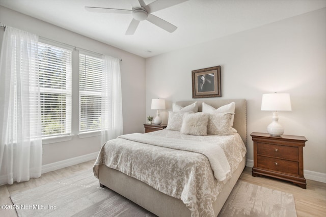 bedroom with baseboards, multiple windows, and light wood-type flooring