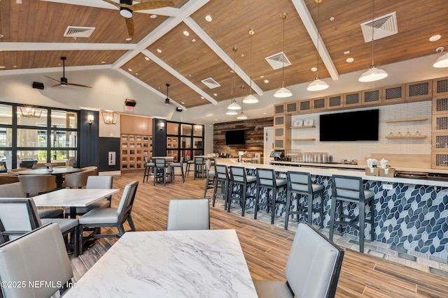 dining area featuring wood finished floors, a ceiling fan, and high vaulted ceiling