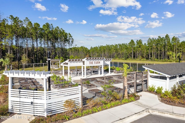 exterior space with a forest view, a pergola, and a vegetable garden