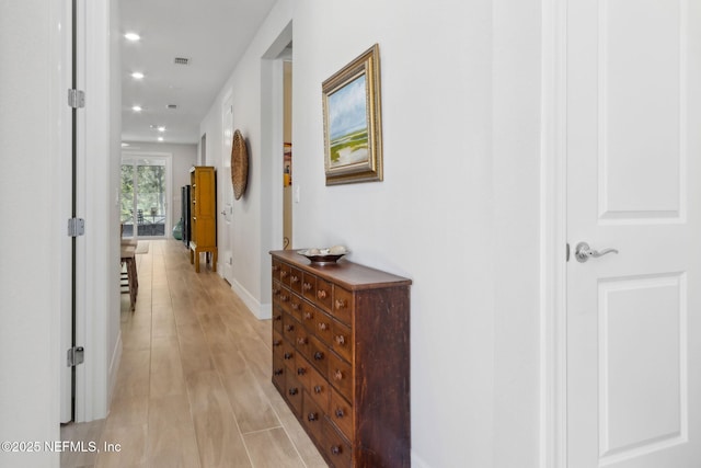 hallway featuring baseboards, visible vents, light wood finished floors, and recessed lighting