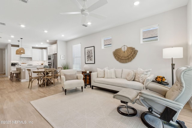 living area featuring ceiling fan, recessed lighting, visible vents, and light wood-style flooring