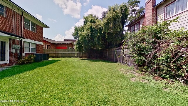view of yard with a fenced backyard and central air condition unit