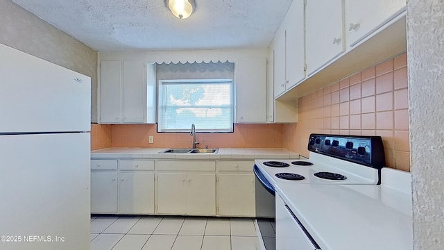 kitchen with tasteful backsplash, electric stove, a sink, white cabinets, and freestanding refrigerator