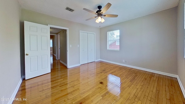 unfurnished bedroom featuring light wood finished floors, baseboards, visible vents, a ceiling fan, and a closet