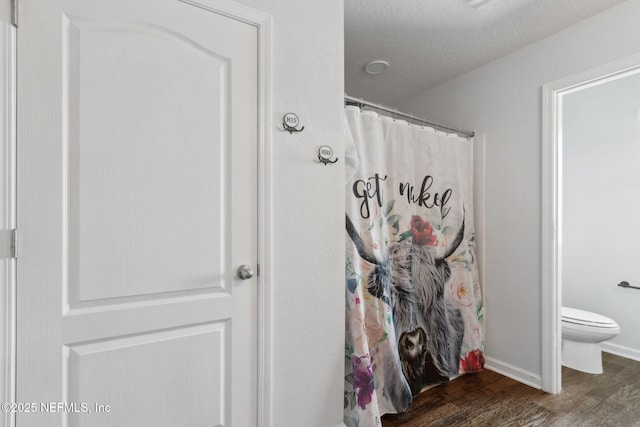 bathroom with toilet, wood finished floors, and curtained shower