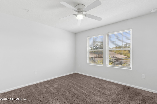 spare room featuring dark colored carpet, baseboards, and ceiling fan