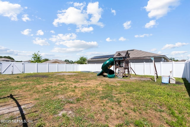view of yard featuring a fenced backyard, a gate, and a playground