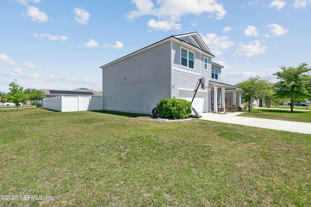 view of side of property featuring a lawn, driveway, fence, and a garage