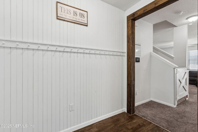 interior space with a textured ceiling, baseboards, and dark wood-style flooring