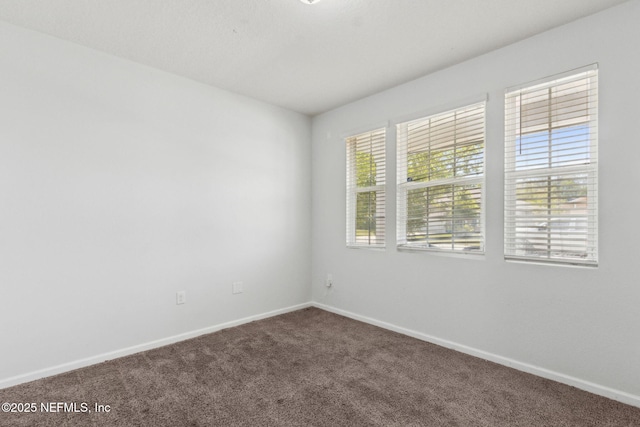 carpeted empty room featuring baseboards