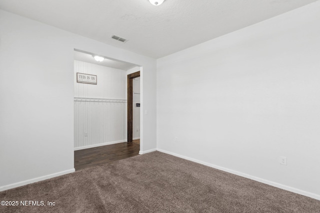 spare room featuring dark carpet, baseboards, and visible vents