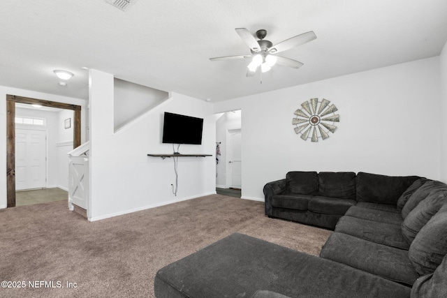 carpeted living room with baseboards, stairs, and ceiling fan