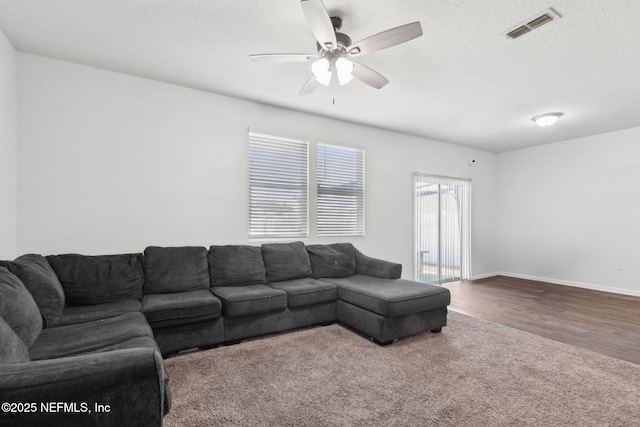 living room with wood finished floors, visible vents, a ceiling fan, and baseboards