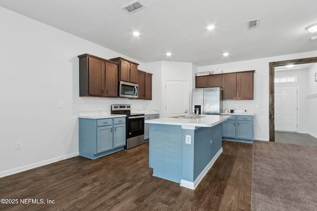 kitchen featuring dark wood-style floors, stainless steel appliances, light countertops, visible vents, and a sink