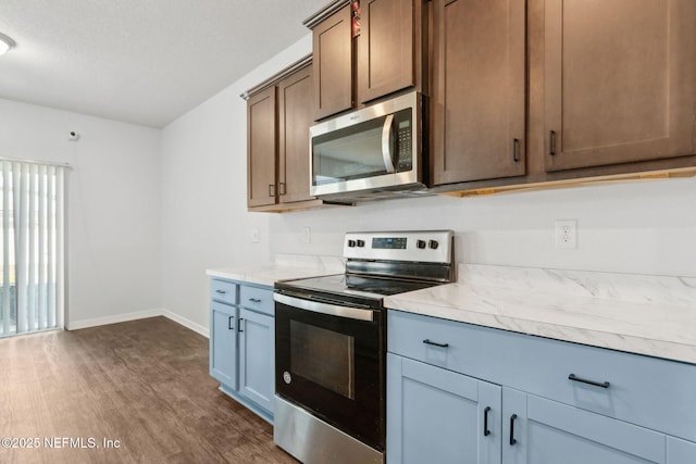 kitchen featuring baseboards, appliances with stainless steel finishes, dark wood-type flooring, and light countertops