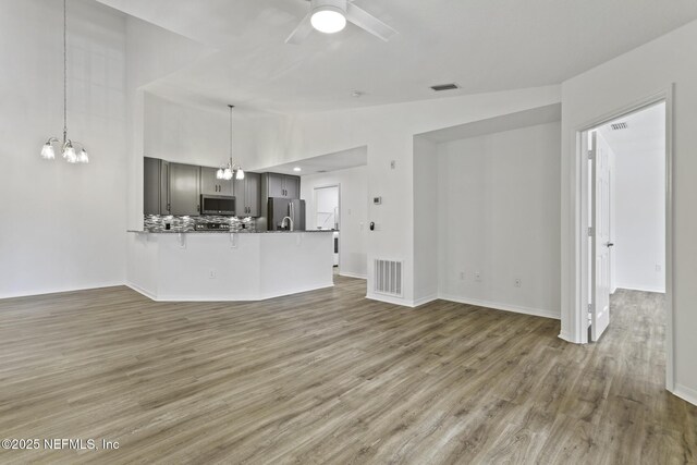 11213 Harbour Vista Cir, Saint Augustine, FL 32080 - unfurnished living room with visible vents, ceiling fan with notable chandelier, wood finished floors, and vaulted ceiling